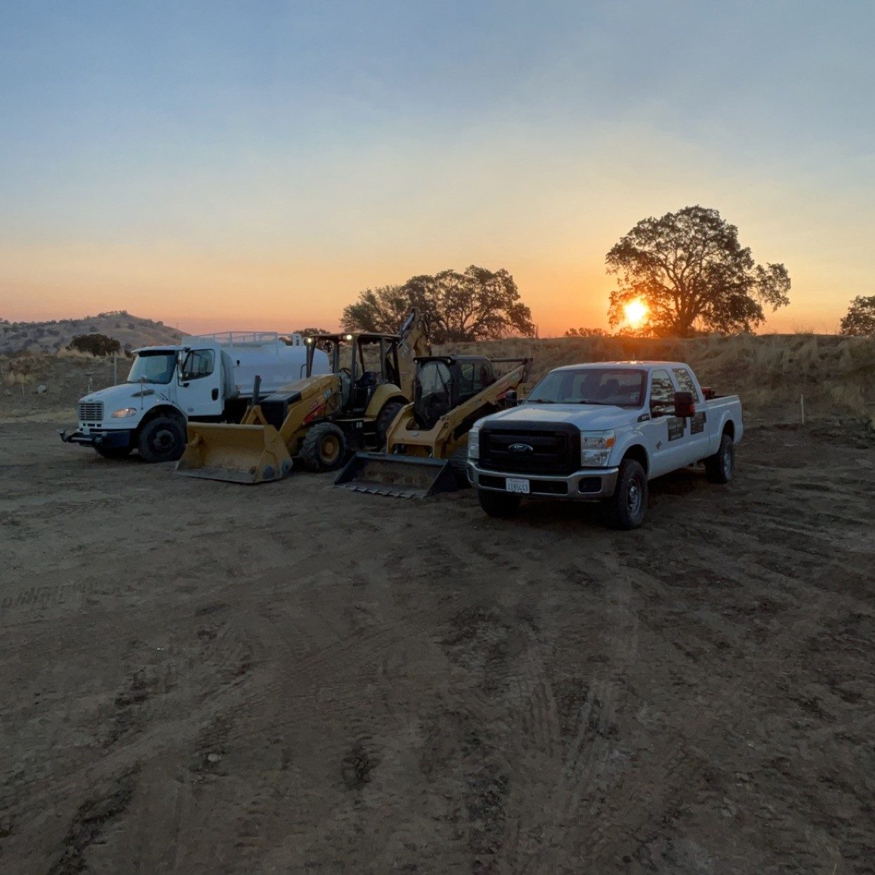 Peak Excavating equipment fleet at sunset on a Central California job site