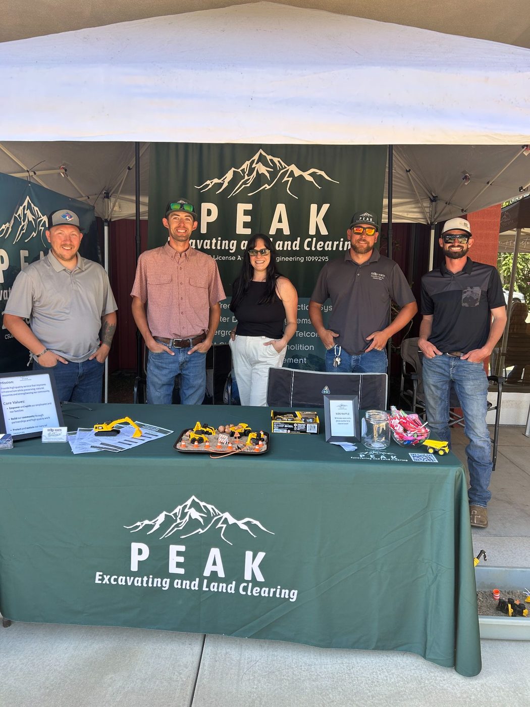 The Peak Excavating team at a community event booth with the PEAK banner